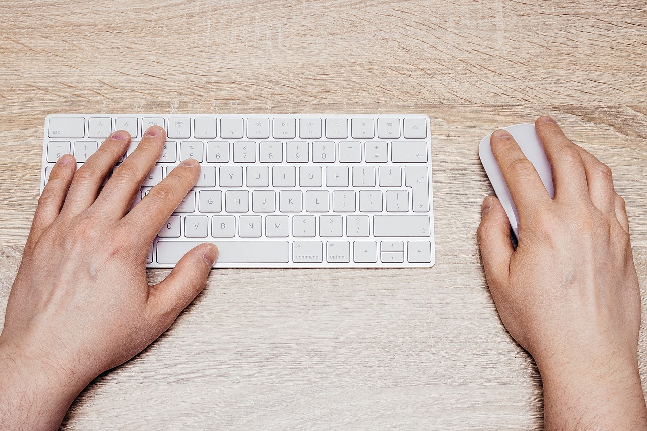A close-up of hands typing on a keyboard, representing the repetitive clicking and typing work an AI computer-use agent takes over