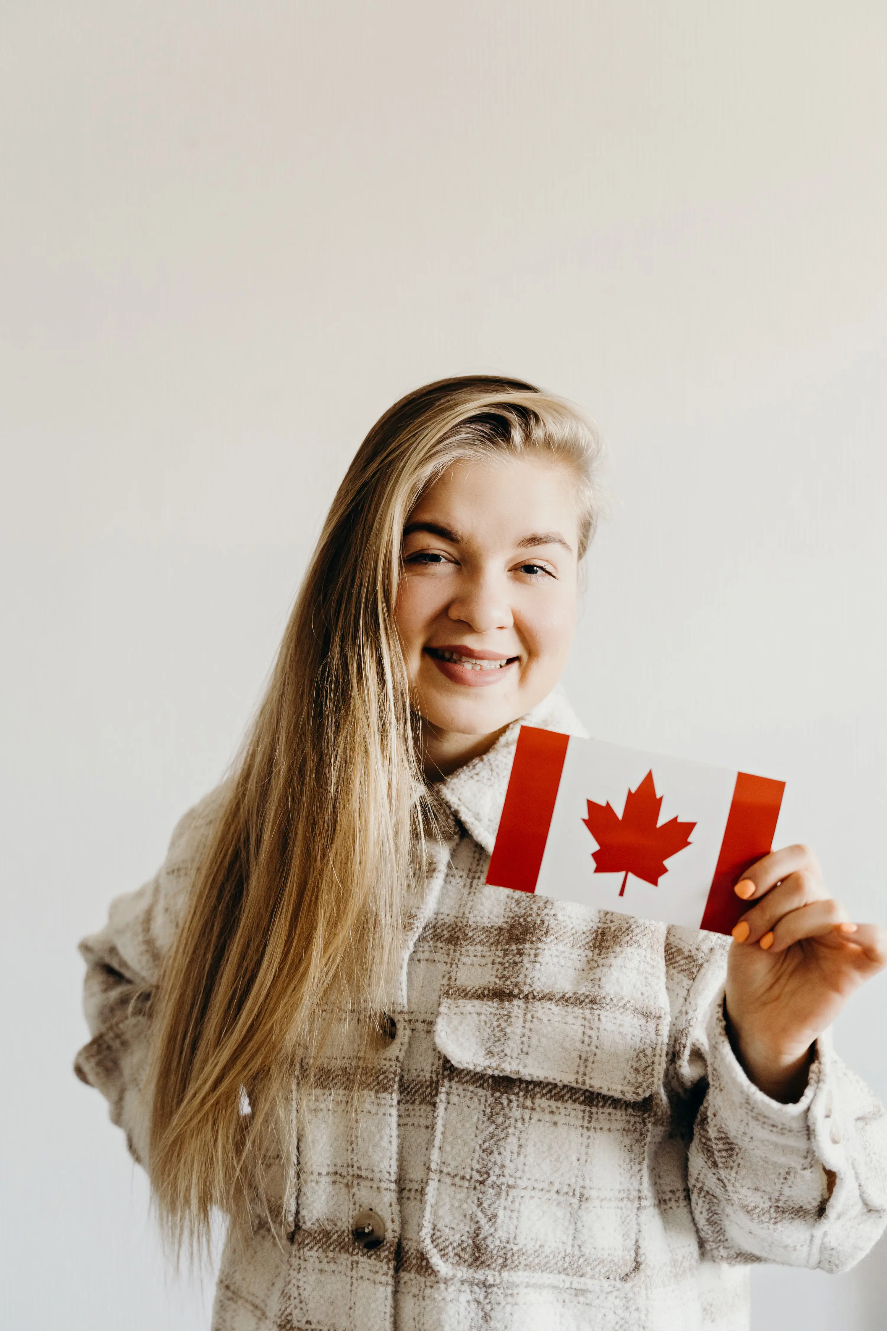 Young woman holding a Canadian flag, representing Indian students planning to study in Canada under the 2026 study permit cap