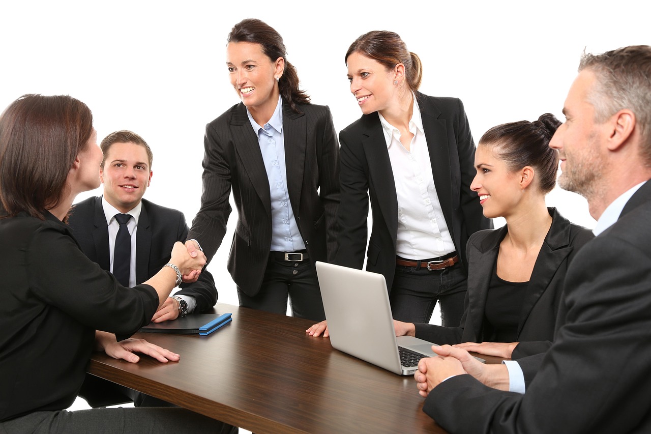 Professionals talking across a table in a business meeting, representing the relationship-based approach that outperforms mass job applications