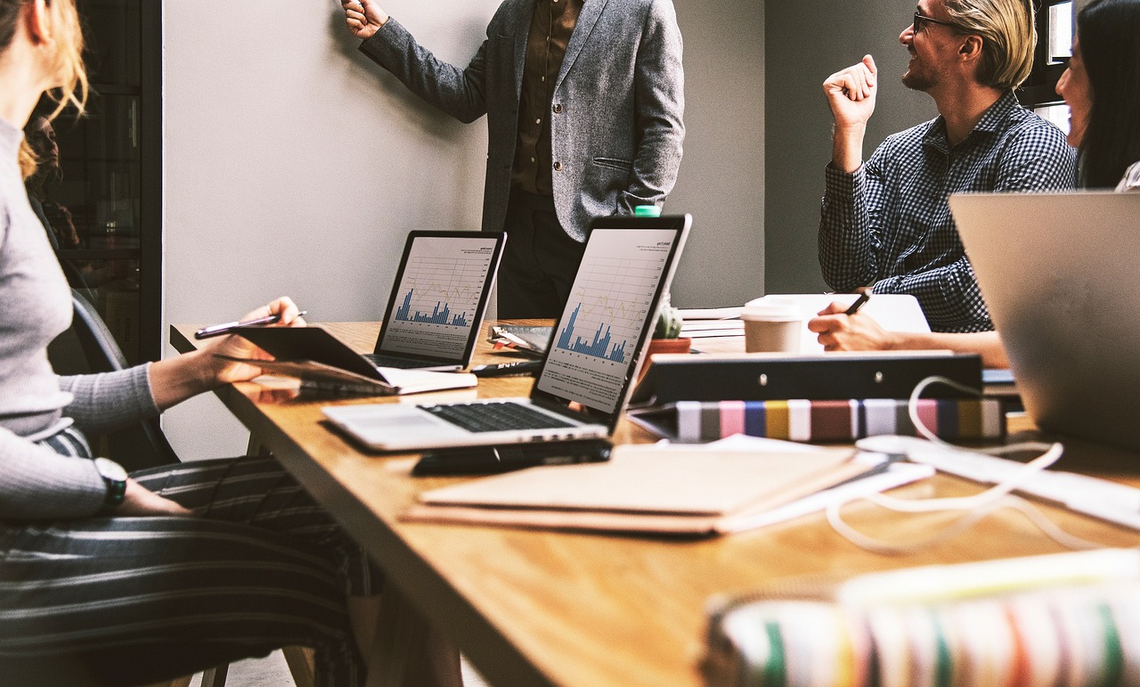 Colleagues working together around a table in an office, representing the staff who collectively become owners when a business converts to an employee ownership trust