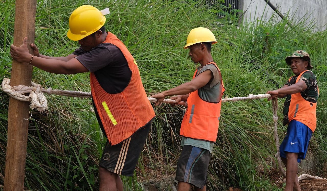 A team of workers pulling together on a rope, representing employees jointly taking on ownership and the debt that funds an employee ownership trust