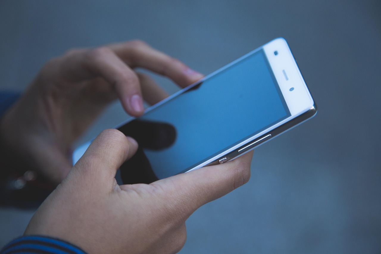 Close-up of a person's hands holding a smartphone and typing a question, representing a customer asking an AI assistant for a recommendation