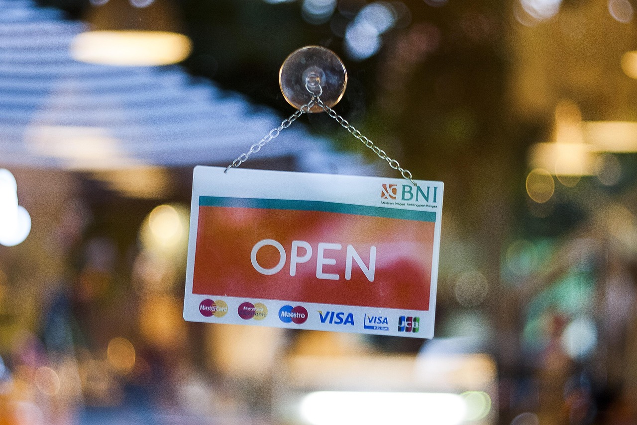 An illuminated Open sign hangs in a small business storefront window, representing Canadian small business owners navigating a 2026 confidence crisis