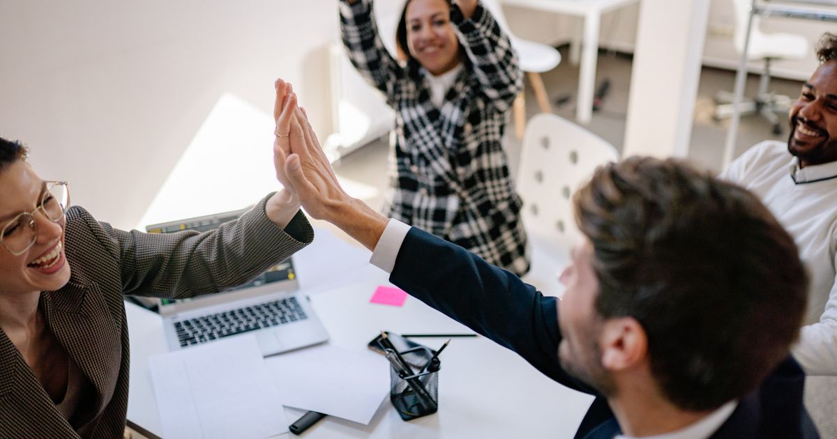 A business team exchanging a high five in a modern office, celebrating a milestone in their AI maturity journey