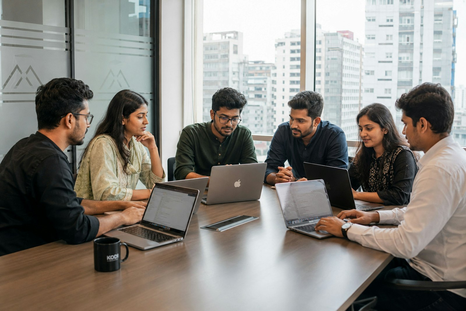 Six colleagues working on laptops around a conference table, representing a team turning research into a shared decision