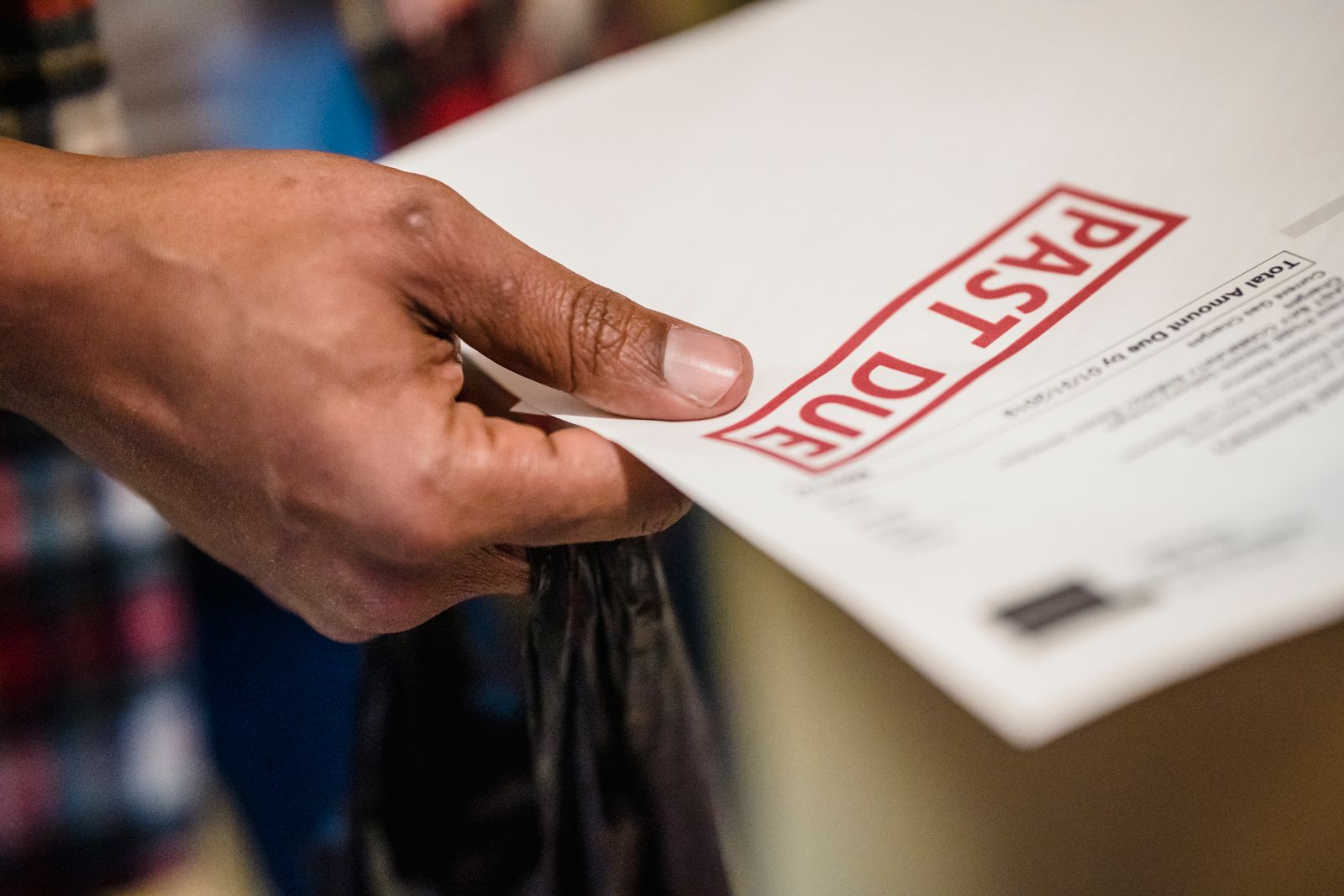 A hand holding an invoice marked with a red PAST DUE stamp