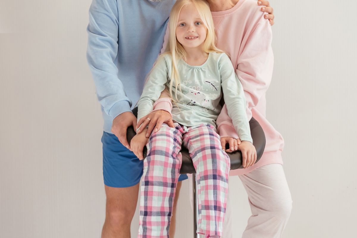 Elderly couple smiling with their granddaughter at home, representing grandparents visiting family in Canada on a Super Visa