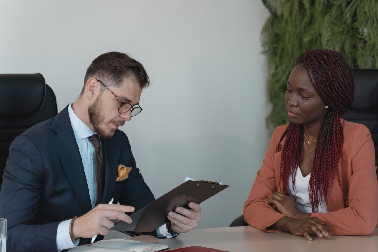 Hiring manager reviewing a candidate's resume across a desk during a job interview, representing AI agents changing entry-level hiring in Canada in 2026