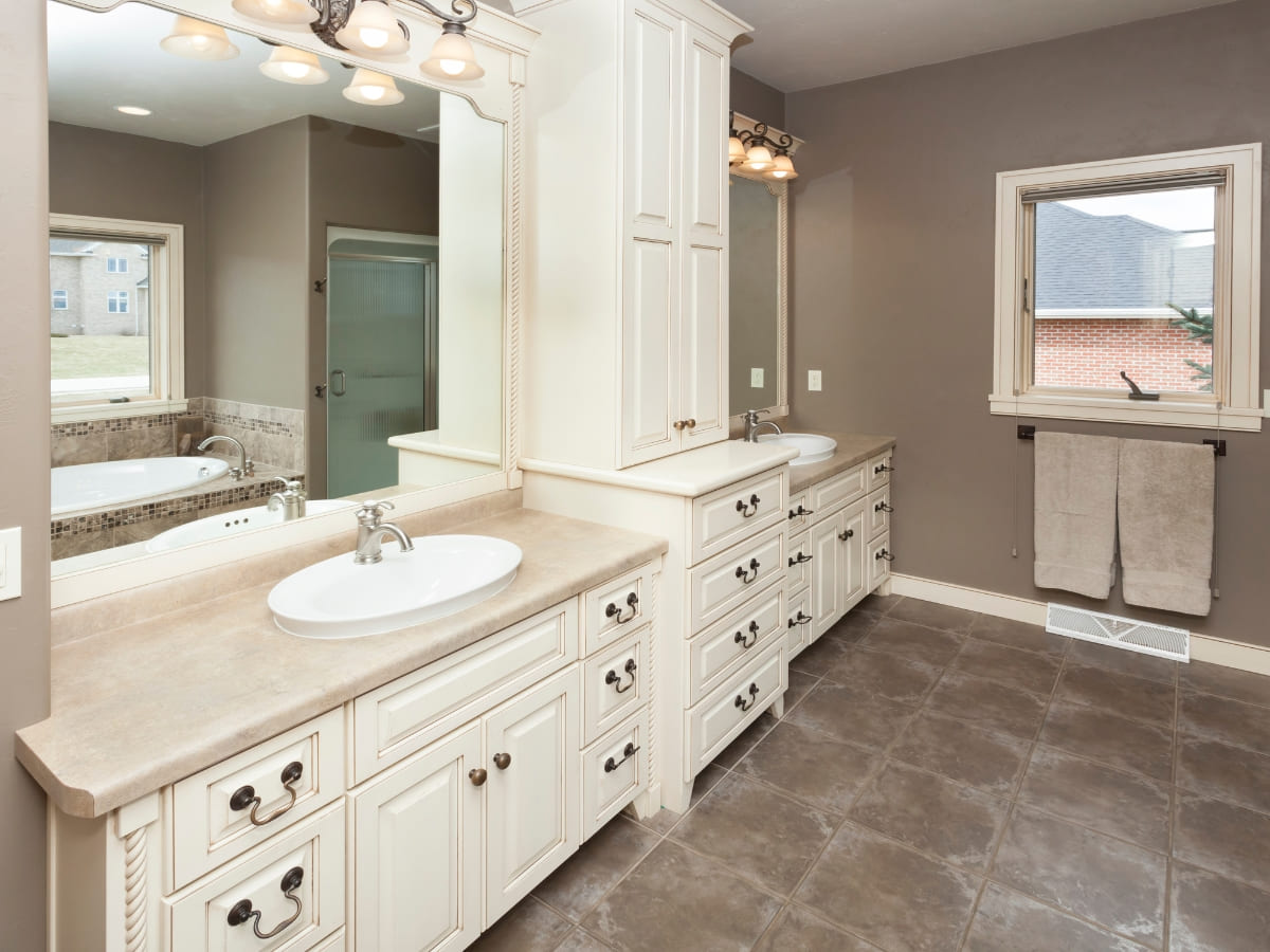 Elegant bathroom with custom-designed white cabinets and dual sinks, featuring ample storage and large mirrors for a refined and functional space.