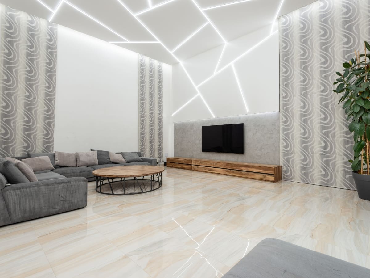 Modern living room with geometric ceiling lights, featuring a large sectional sofa and minimalist decor, designed for both style and comfort.