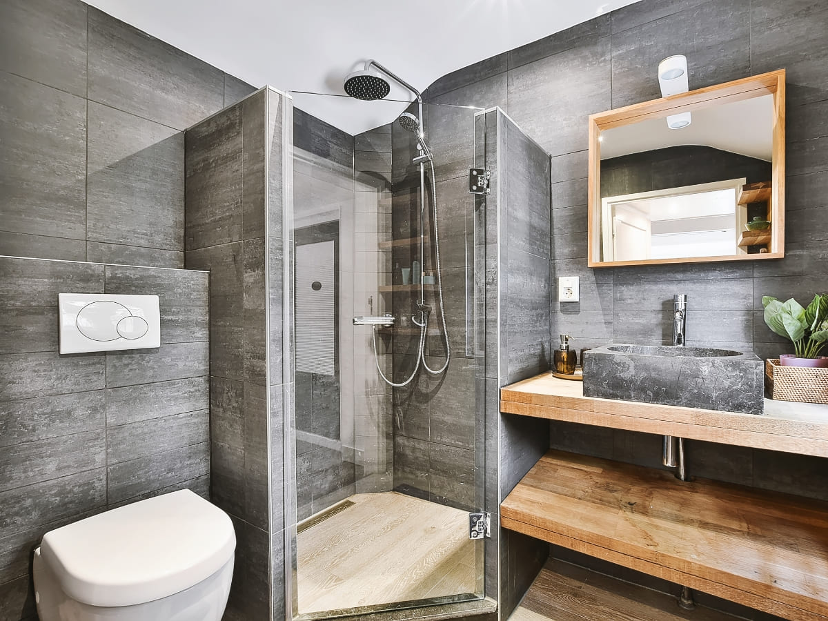 Modern bathroom with a glass-enclosed shower, dark gray tiles, and a contemporary vanity with a stone sink, designed for a luxurious and clean look.