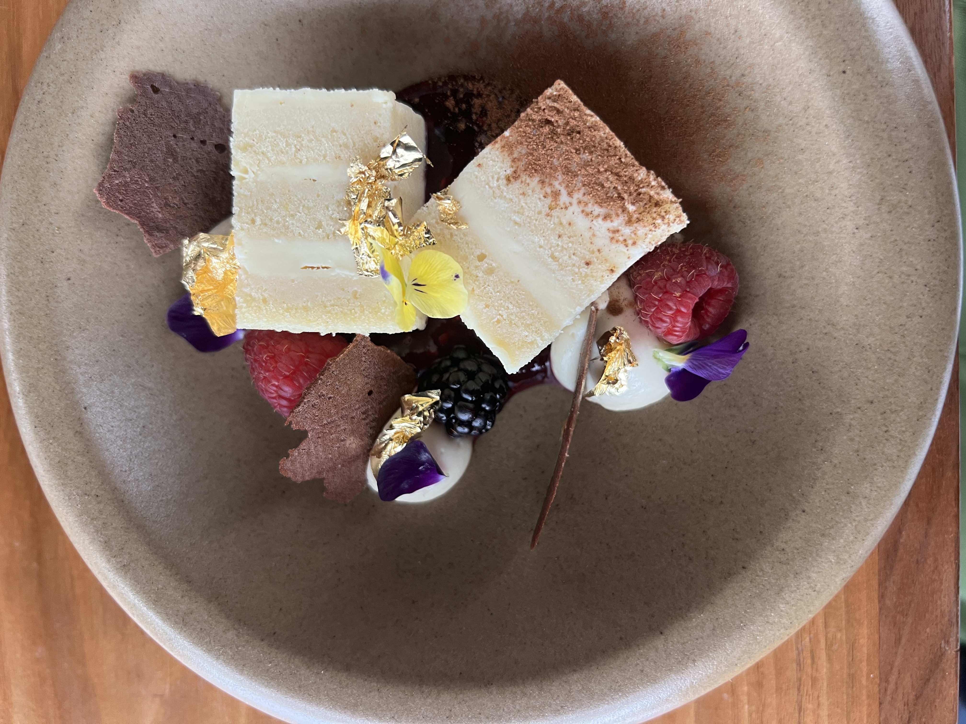 Plated dessert with cream, berries, and edible gold