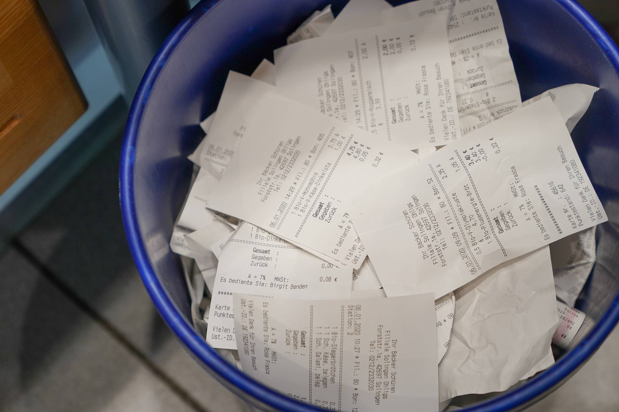 Des tickets de caisse jetés dans une poubelle, illustrant le gaspillage d’opportunités de cashback.