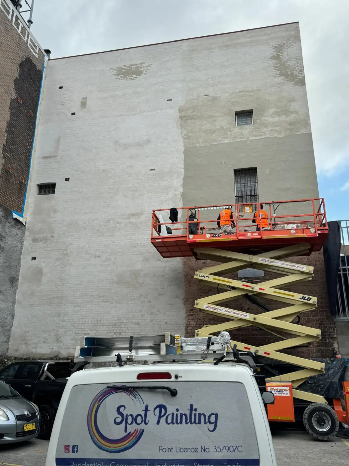 Spot Painting crew repairing a building facade from an elevated work platform in Sydney