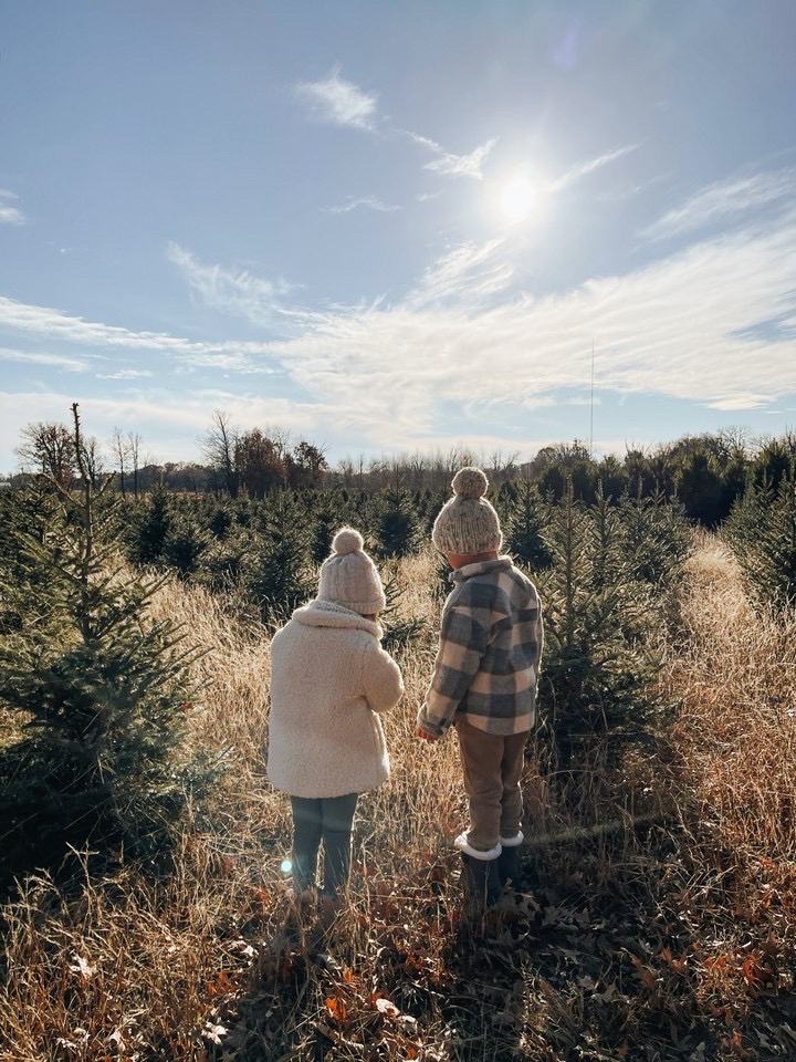 Two kids in knit hats look out over the rows at golden hour