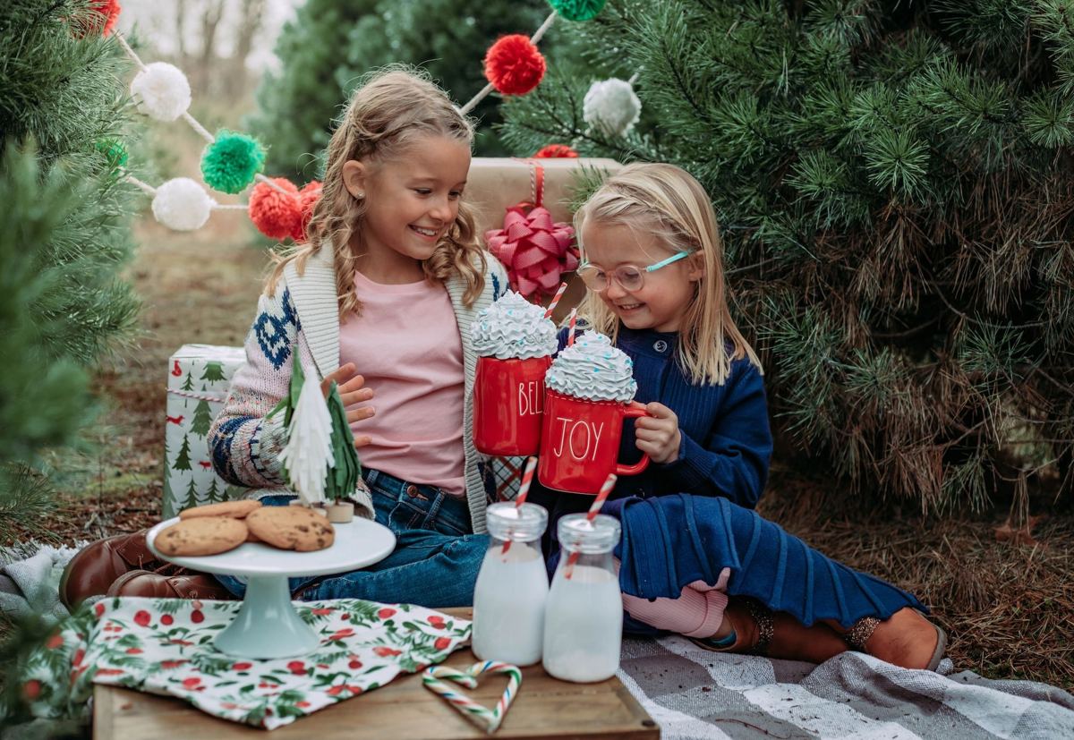 Two girls with mugs of hot chocolate and cookies among the trees