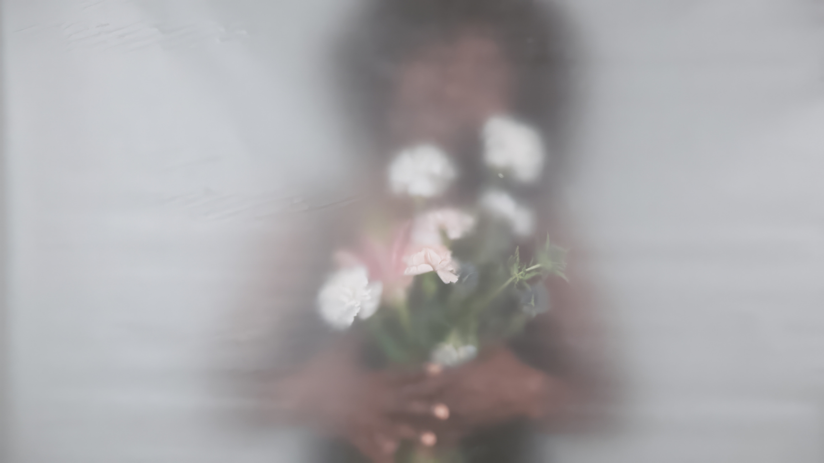 Hands holding a bouquet of soft white and pink flowers