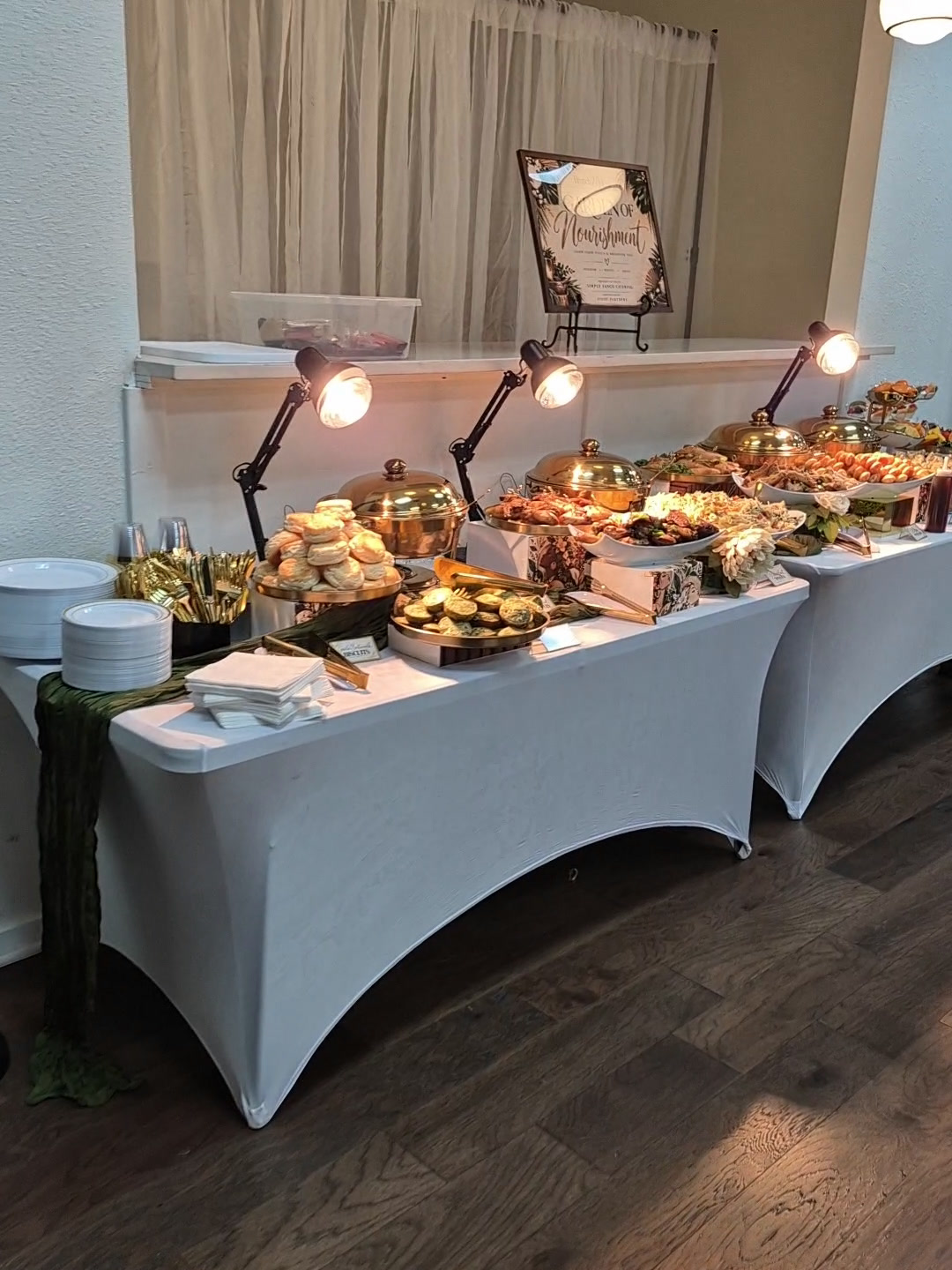Brunch buffet tables with white linens, gold serving dishes, tiered food displays, greenery, and warming lamps