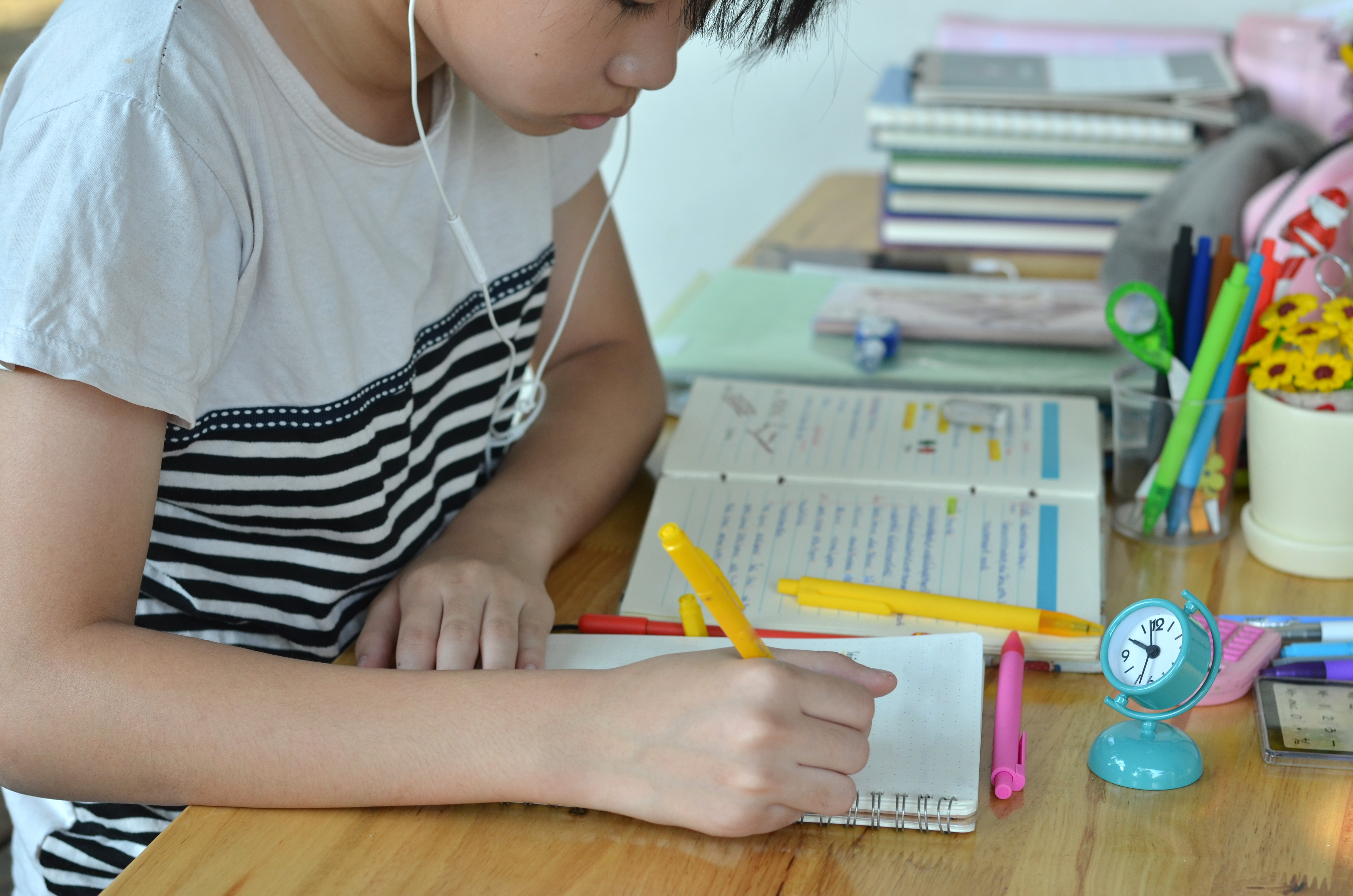 Student working on a writing assignment with notes and study materials spread across a desk.