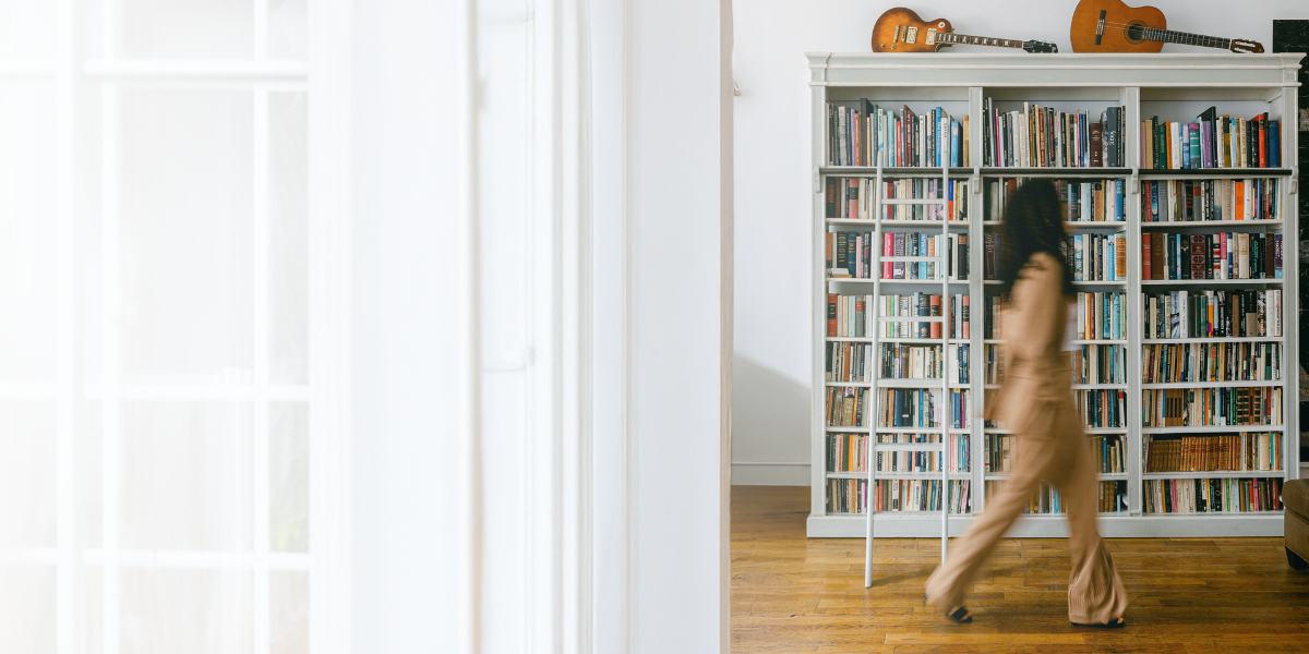 A founder walking past a wall of bookshelves in a bright room