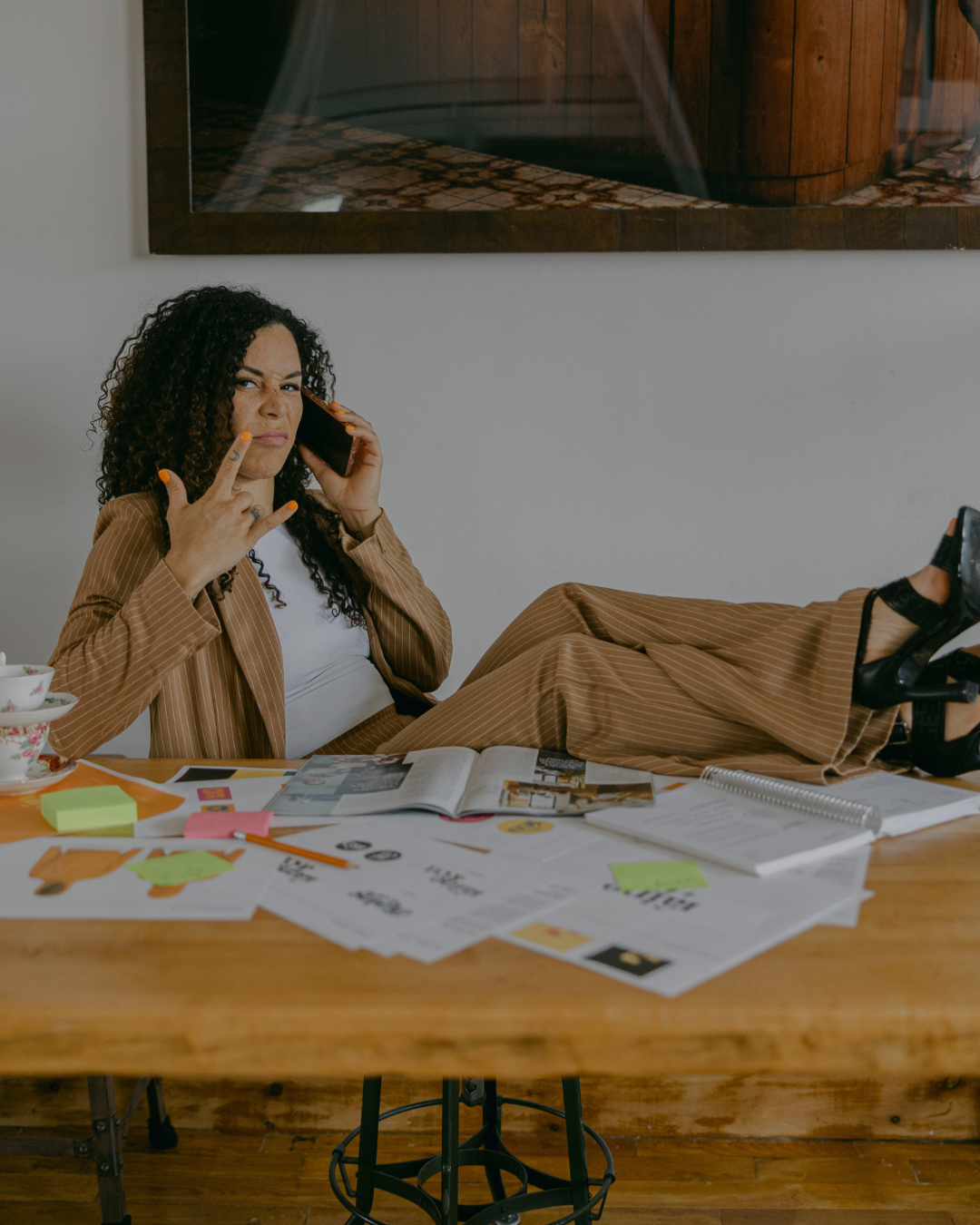 A business owner on the phone with her feet up on a desk covered in papers