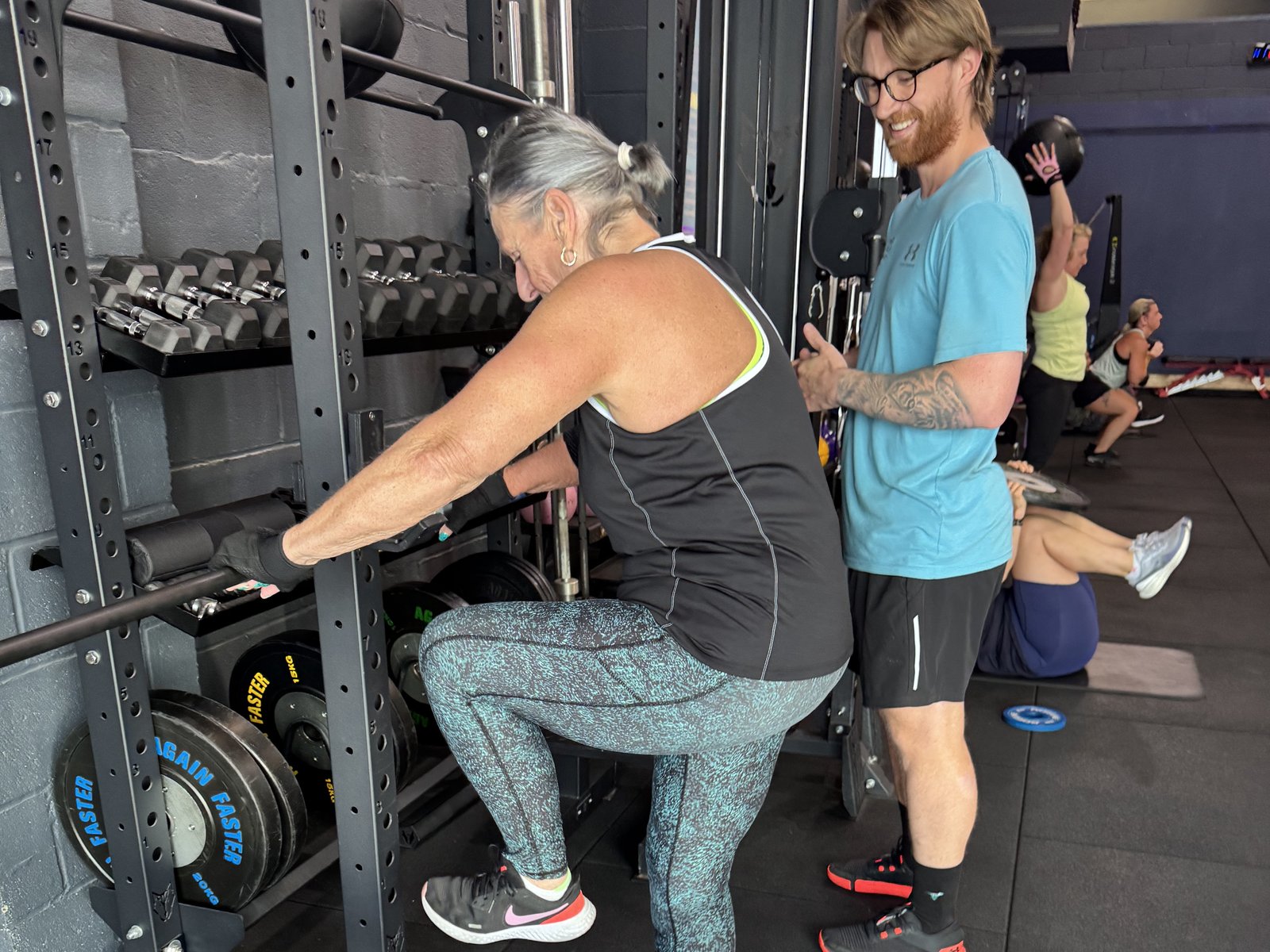 Infinity coach smiling as a member works through step-ups