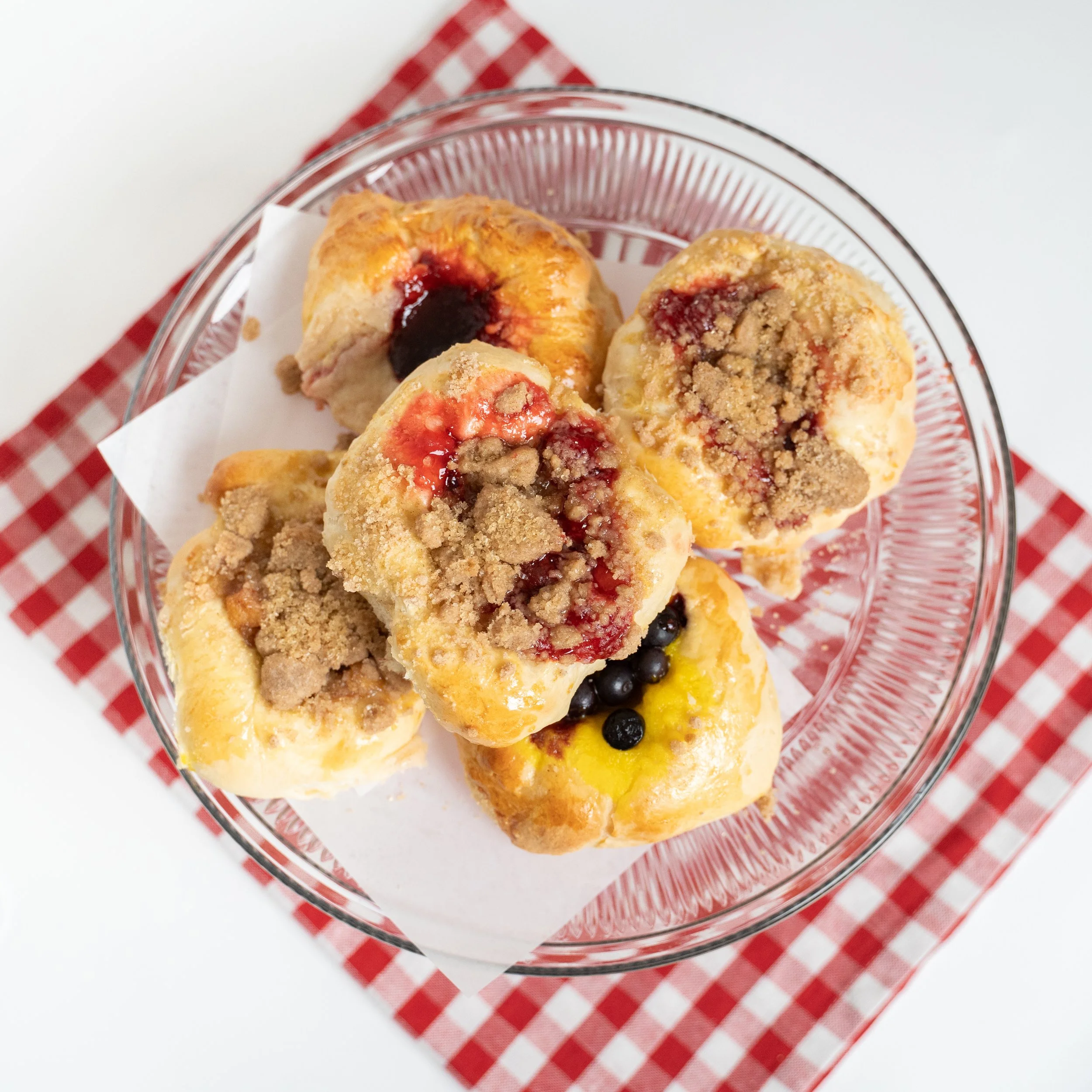 Crumble-topped fruit kolaches on a red-checkered napkin