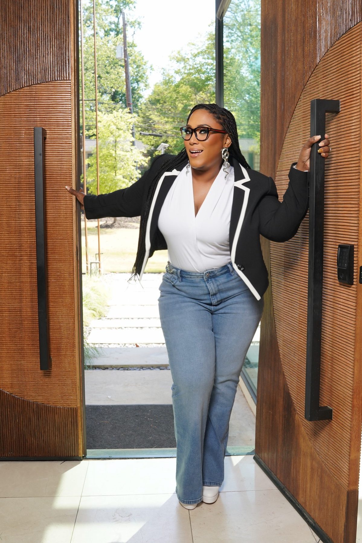 Dr. Lynda A. Barnes opening a tall wooden front door and smiling