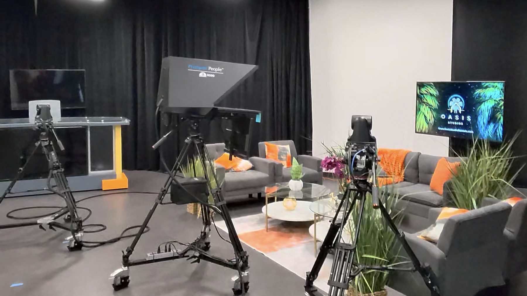 Television studio with three camera pedestals, a teleprompter, a news desk and an interview set
