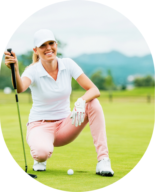 Woman smiling sitting near a golf ball in the hole holding a golf club, representing accelerated progress through clearing subconscious blocks with personalized golf mindset programs.