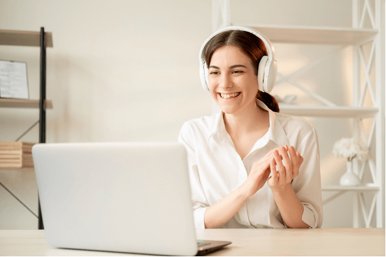Smiling woman having a virtual coaching session on her laptop, representing personalized 1-on-1 emotional breakthrough coaching.