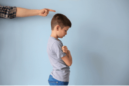 A child stands alone, visibly upset after being punished for showing emotion—depicting the internalized belief 'Showing emotion makes me weak.' This image highlights how trauma and emotional suppression in childhood lead to subconscious patterns that influence emotional regulation and confidence, addressed through emotional healing with the Biko Method.