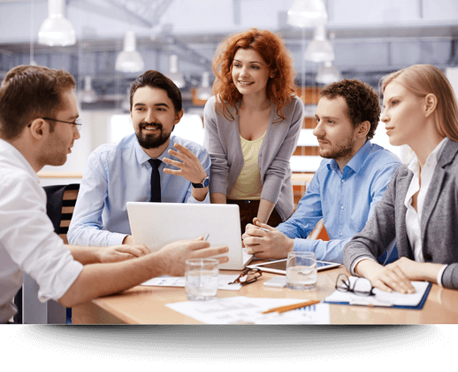 Workmates smiling and collaborating at a table in an office setting, illustrating the benefits of group sessions designed to improve emotional wellness and resilience among employees.