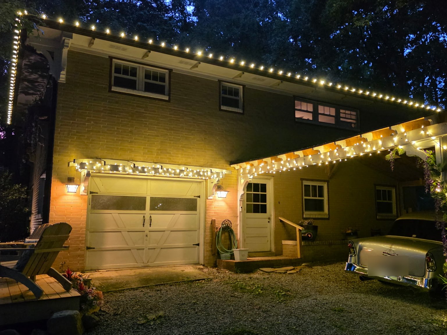 Home with warm white Christmas lights on the roofline, garage and carport