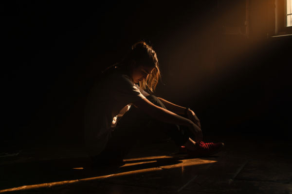 A person sitting alone after a tough moment (e.g., looking down or reflective), but with soft sunlight hitting them—symbolizing growth through humility.