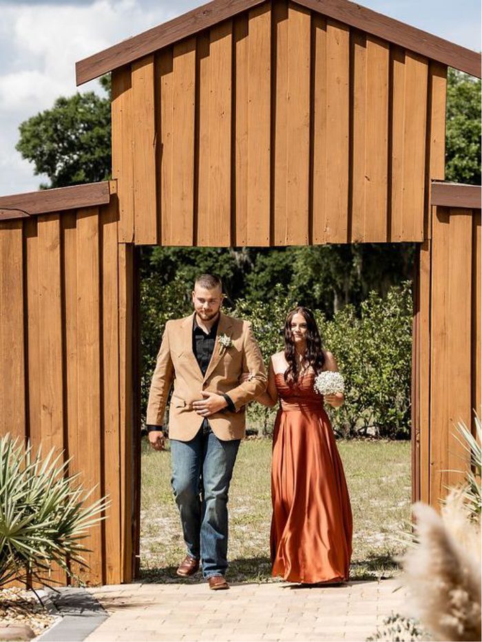 A couple walking through the timber ceremony gate