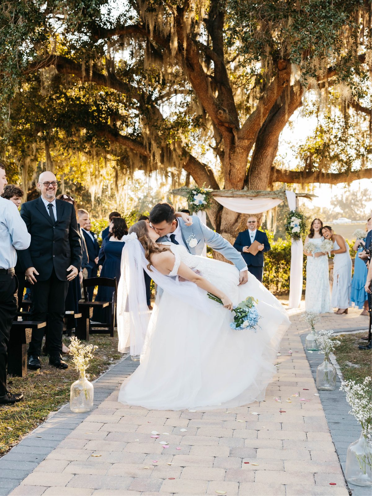 A groom dipping his bride on the paver aisle after the ceremony