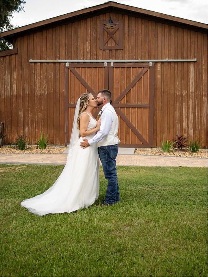 A couple kissing in front of the barn's sliding doors