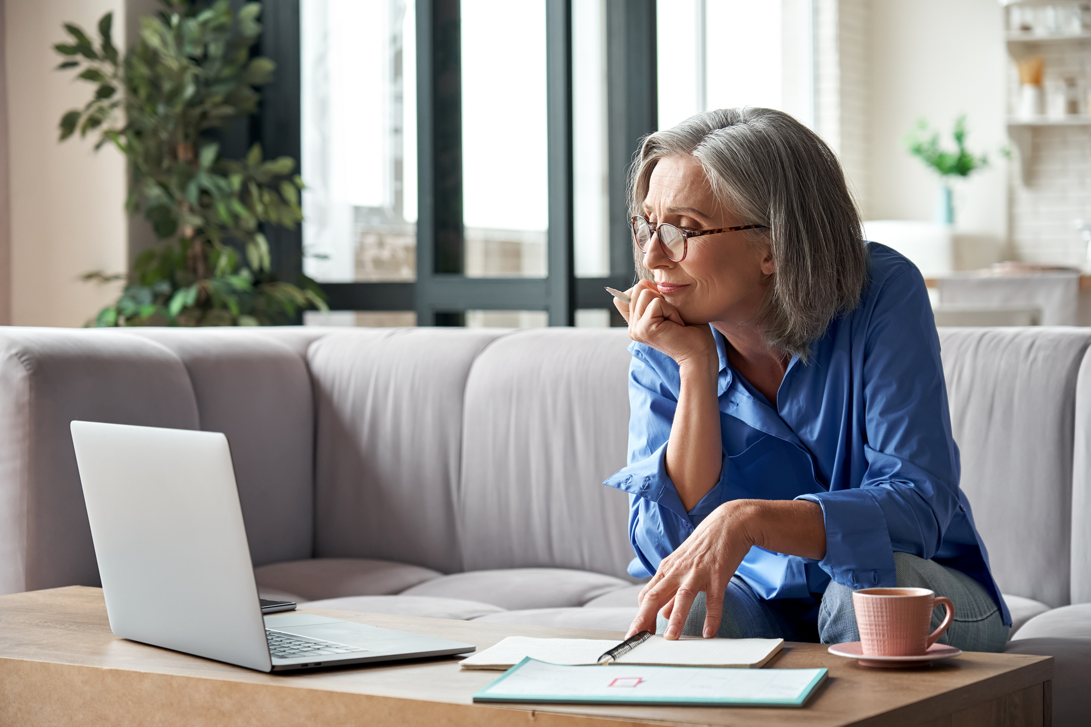A retired woman reviewing her benefits on a laptop at home