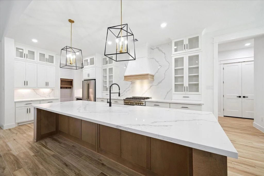 Finished kitchen with a large island, white cabinets, and pendant lighting