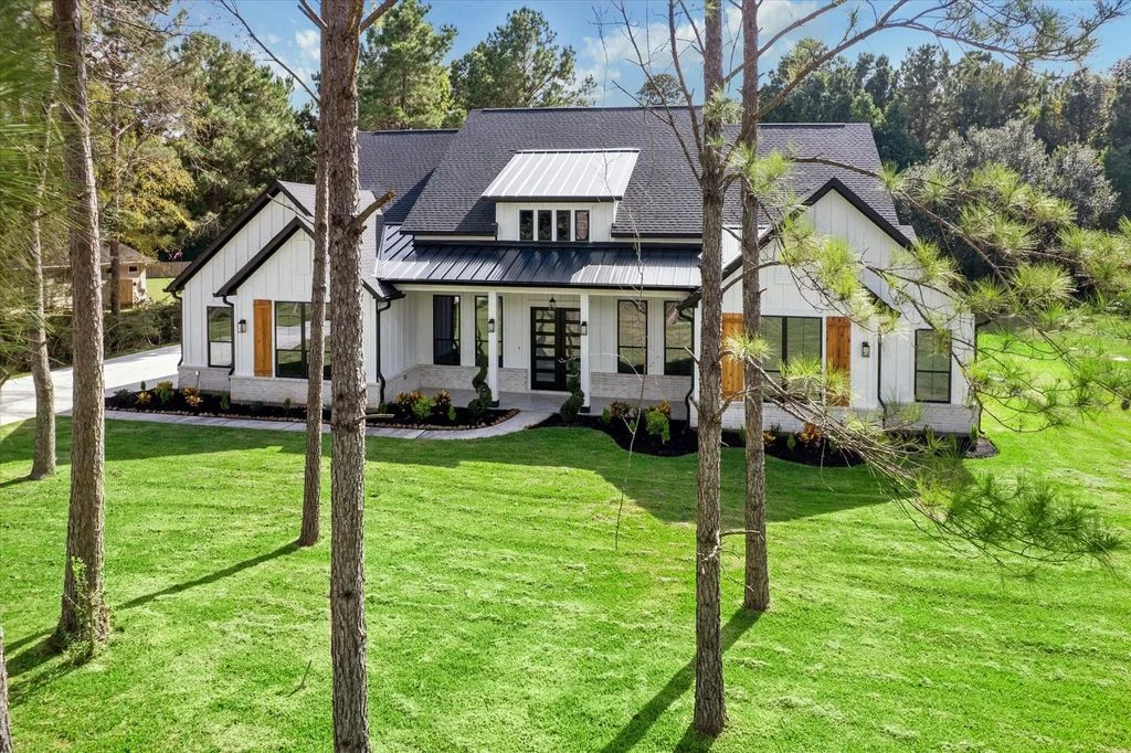 Completed white home built by Dustin, with black roof accents and mature trees