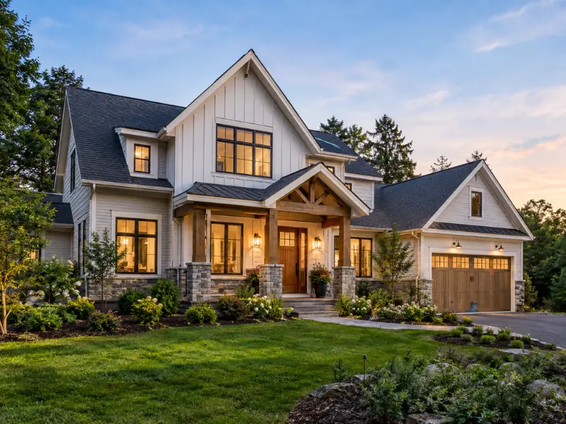 Finished custom home in Exeter, NH with board-and-batten siding, stone piers, and a timber-framed entry.