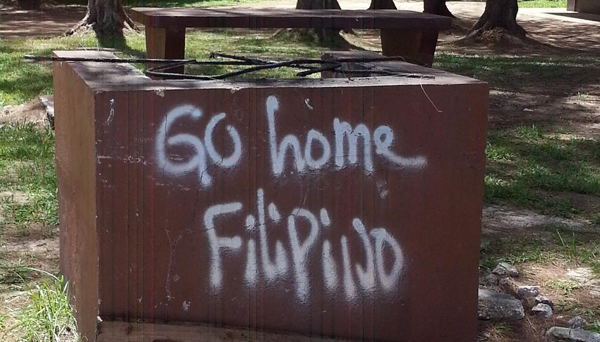 Street scene in Saipan showing a concrete wall with anti-immigrant graffiti Street scene in Saipan showing a concrete wall with anti-immigrant graffiti