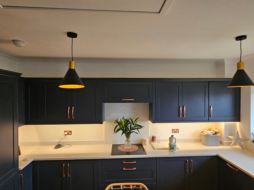 Freshly painted modern kitchen with blue cabinets and feature wall in Rogerstone home