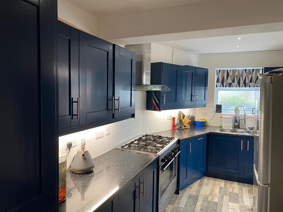 Freshly painted modern kitchen with blue cabinets and feature wall in Rogerstone home
