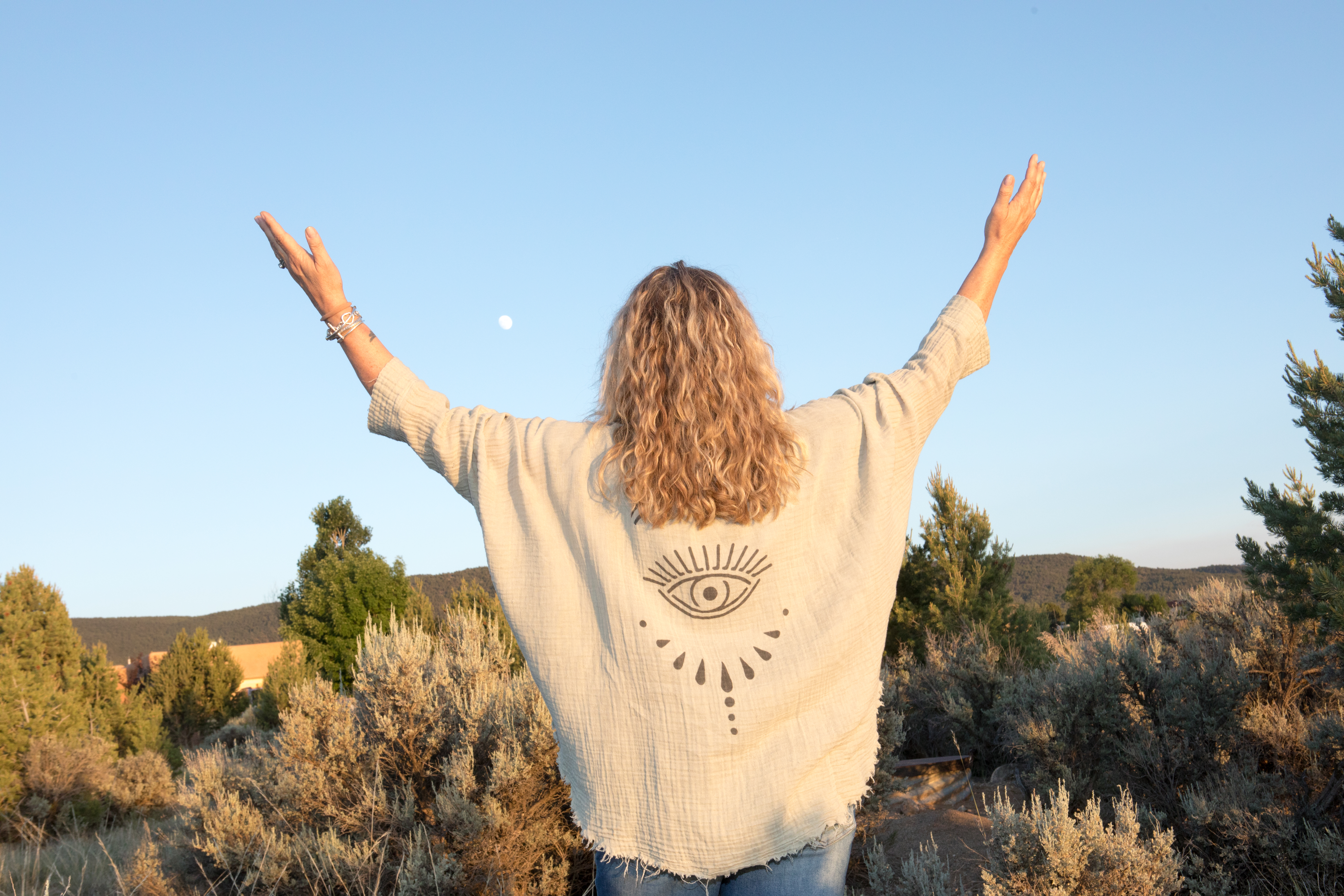Jen with arms raised to the moon over the high desert