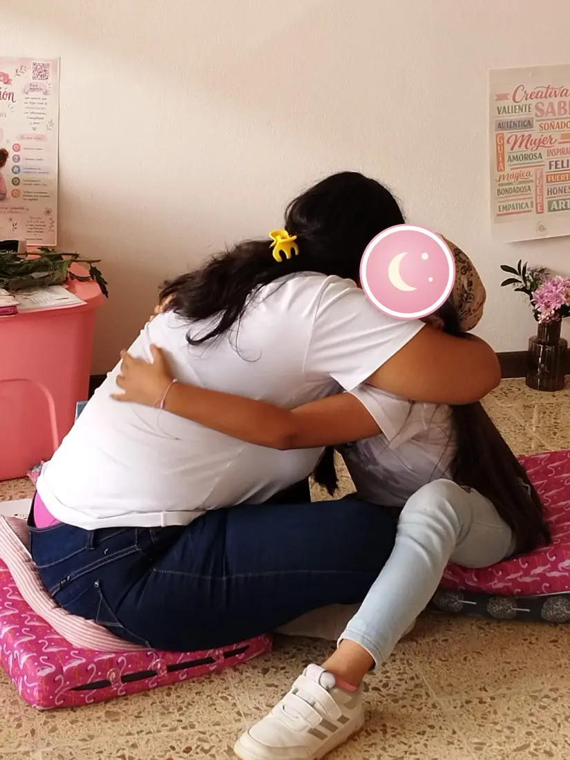 Una mamá y su hija se abrazan durante el taller.