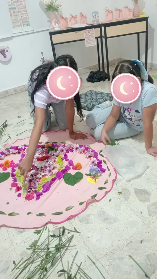 Dos niñas arman un mandala con pétalos de flores.
