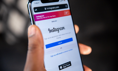 Hand holding a smartphone displaying the Instagram login page, representing mobile access to social networking and content sharing.
