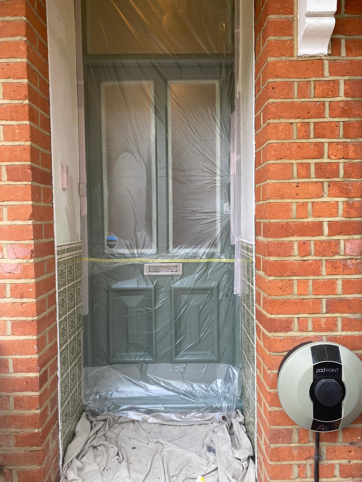Front door professionally masked with protective sheeting before painting in Epsom